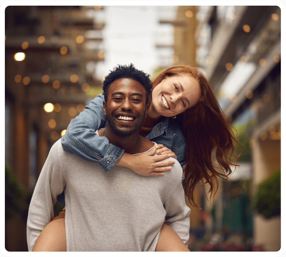 Happy couple piggybacking on city street