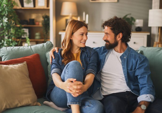 Smiling couple enjoying time together at home, sitting on a comfortable sofa, having a pleasant conversation