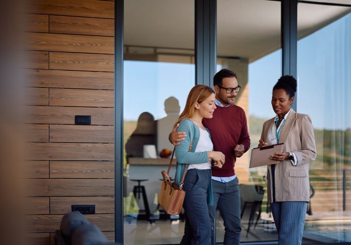 African American real estate agent going through housing plans with a couple who is buying a new home. Copy space.